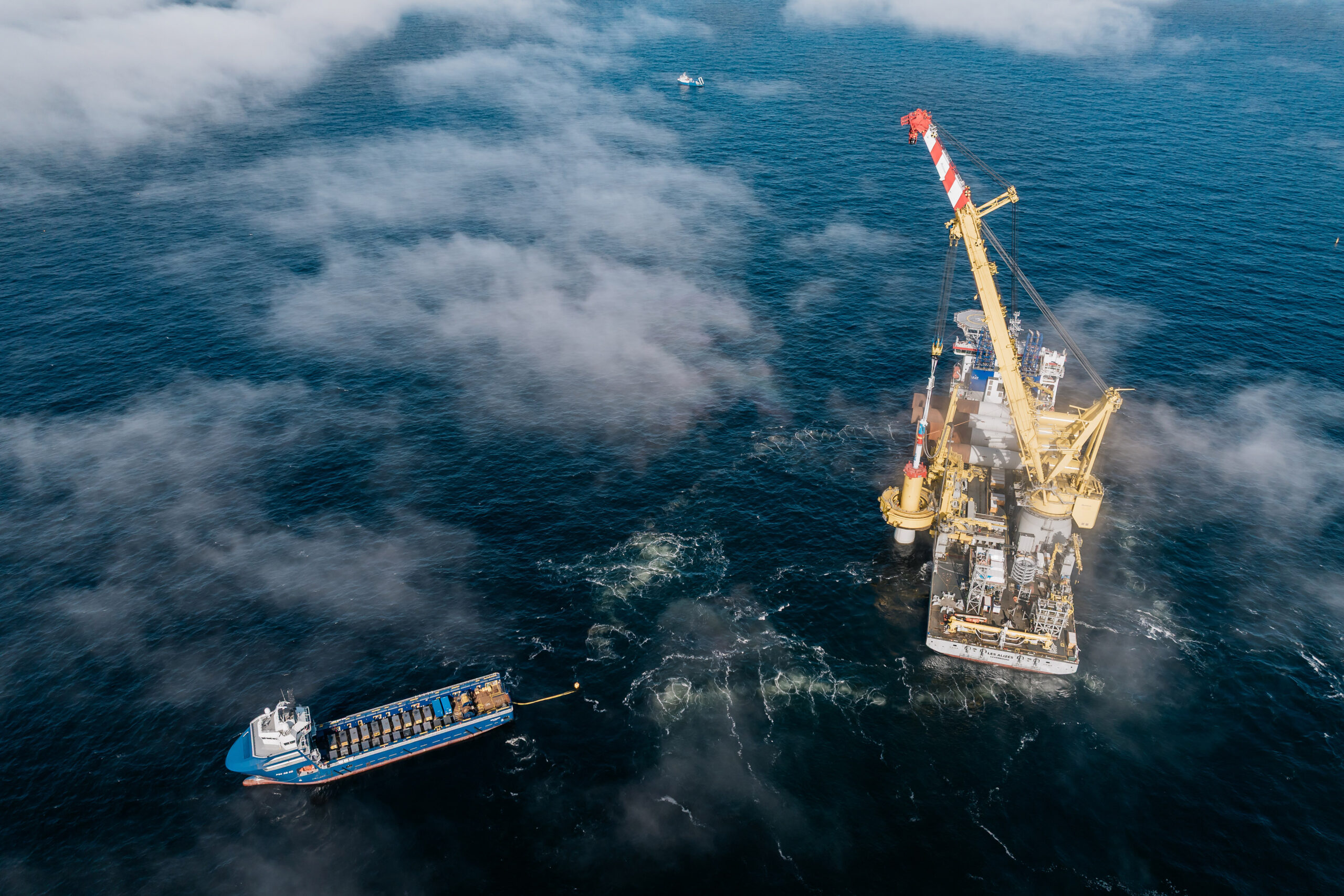 Top-down aerial drone view of the Jan De Nul ship Les Alizés lowering the first steel monopile foundation at the RWE THOR offshore wind farm near Thorsminde, Denmark, on April 29, 2025, surrounded by calm sea.