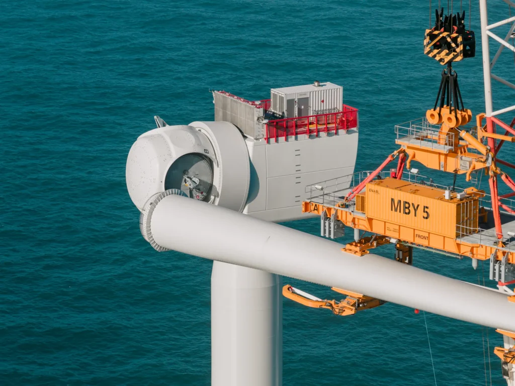 Ein Blatt das mit einem MBY an einem Kran an der Gondel einer Offshore Windturbine montiert wird.