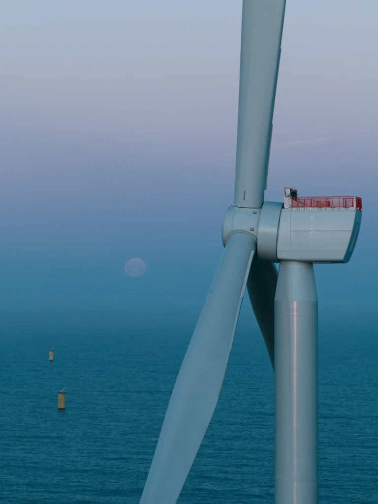 Windturbine in der Nordsee mit dem untergehenden Mond im Hintergrund.