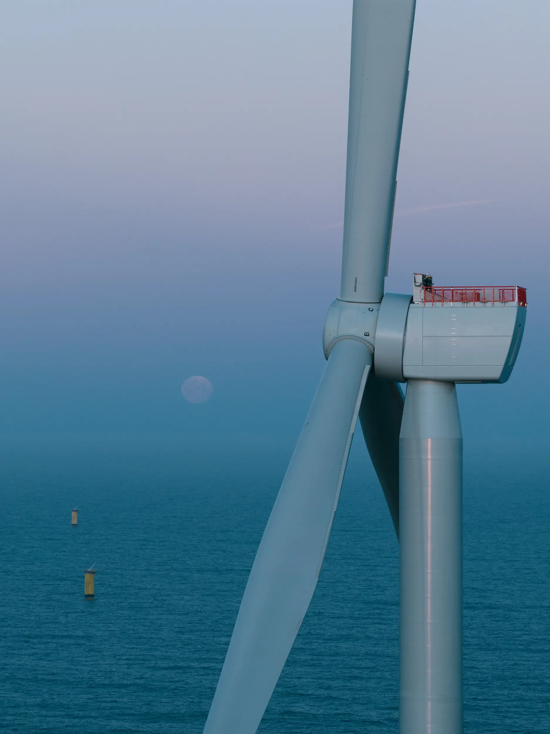 Windturbine in der Nordsee mit dem untergehenden Mond im Hintergrund.